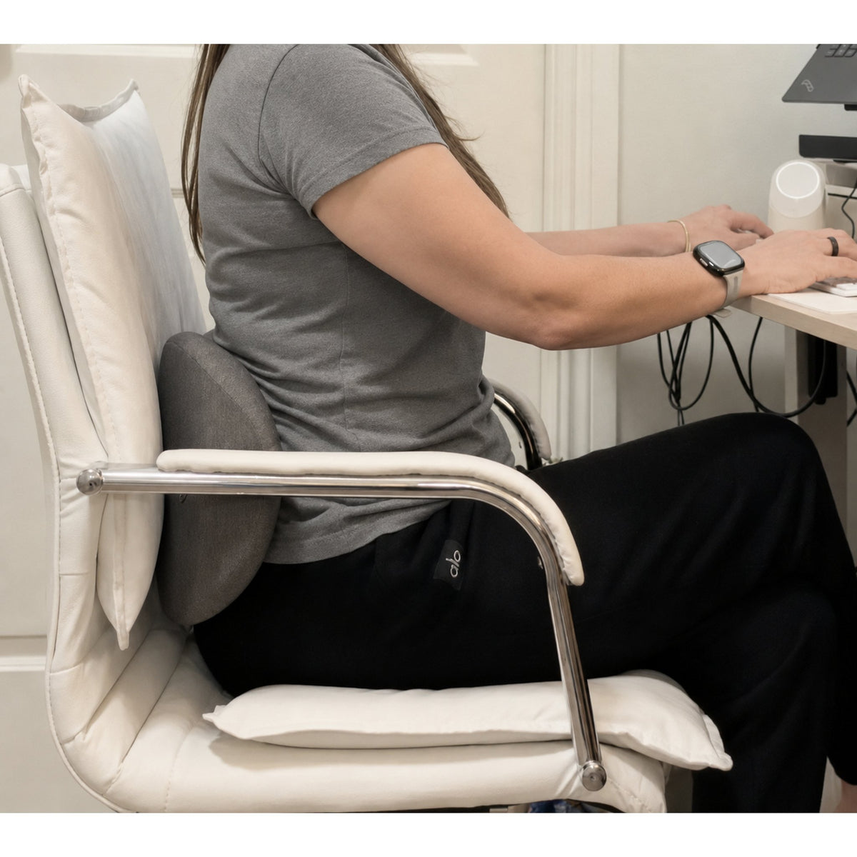 Person at a desk using the Orevive SpineEase massager as lumbar support while working