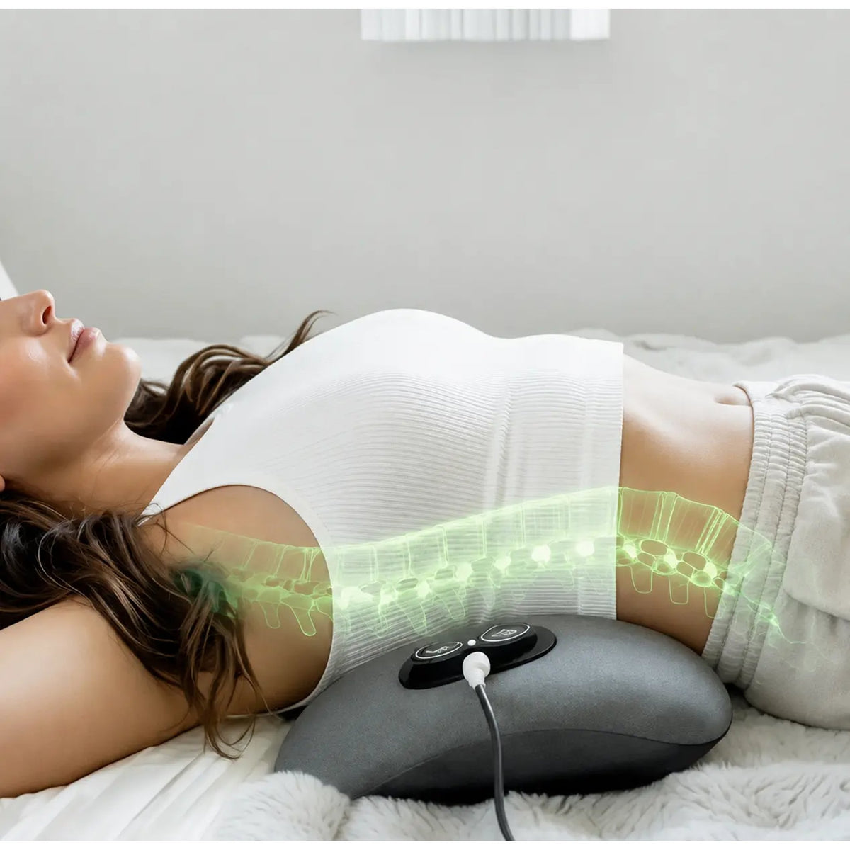 Woman lying in bed with the Orevive SpineEase massager warming her lower back
